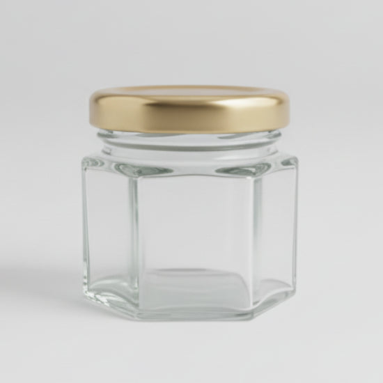 Small hexagonal glass jar with a gold lid on a black background