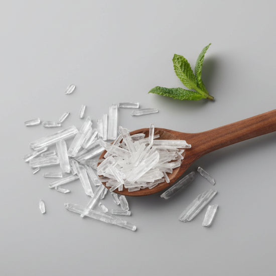 Wooden spoon with crystals and a sprig of mint on a dark surface