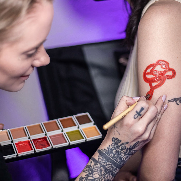 Tattoo cover-up demonstration applying palette to red rose tattoo on arm