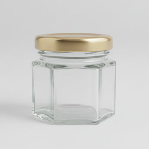 Small hexagonal glass jar with a gold lid on a black background