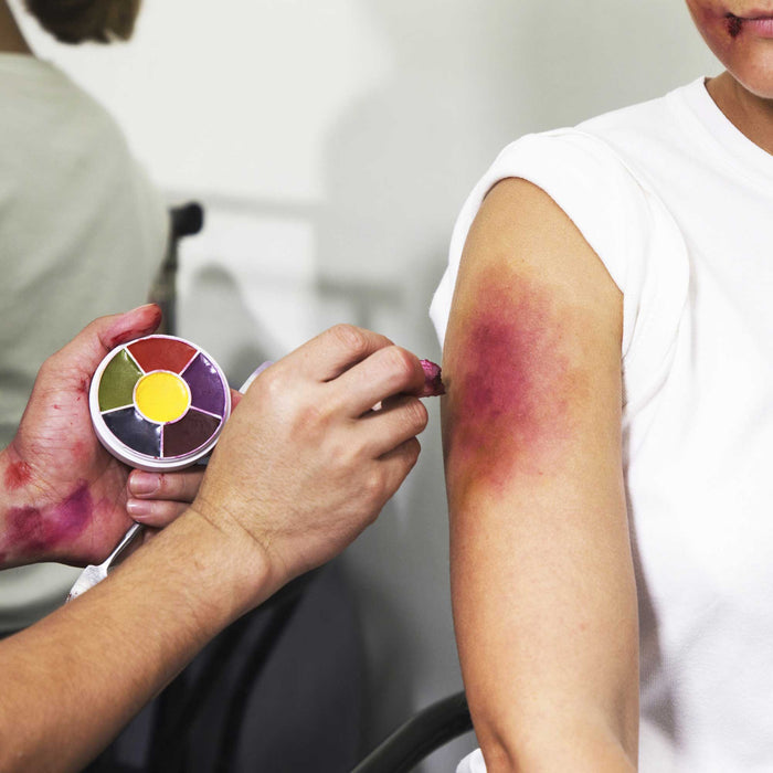 Makeup artist applying Bruise Wheel to model's shoulder bruise SFX