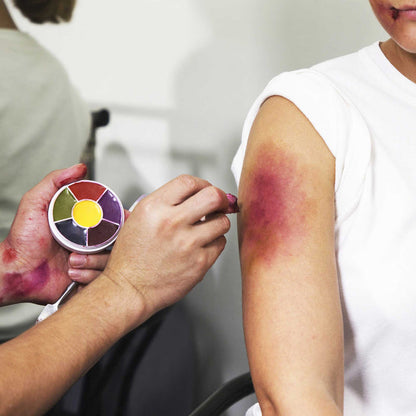 Makeup artist applying Bruise Wheel to model's shoulder bruise SFX