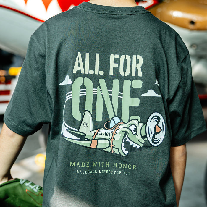 Close up of Youth Dark Grey T- shirt with green cartoon airplane graphic and lettering that says 'ALL FOR ONE Made with honor Baseball Lifestyle 101' on person
