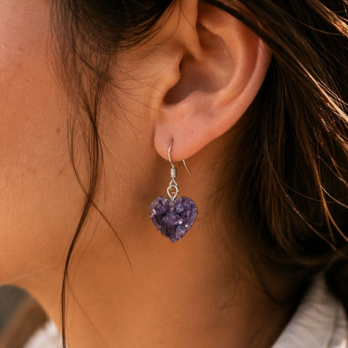 Close-up of a person wearing a purple heart-shaped earring.