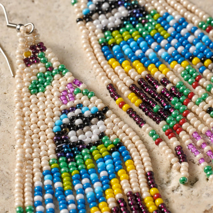 Beaded bird fringe earrings by Ten Thousand Villages featuring colorful beads and intricate bird design, hanging with fringe details.