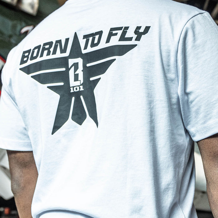 Close up of Youth white t-shirt with black “BORN TO FLY” lettering, black star, and white BL101 logo centered inside the star on person