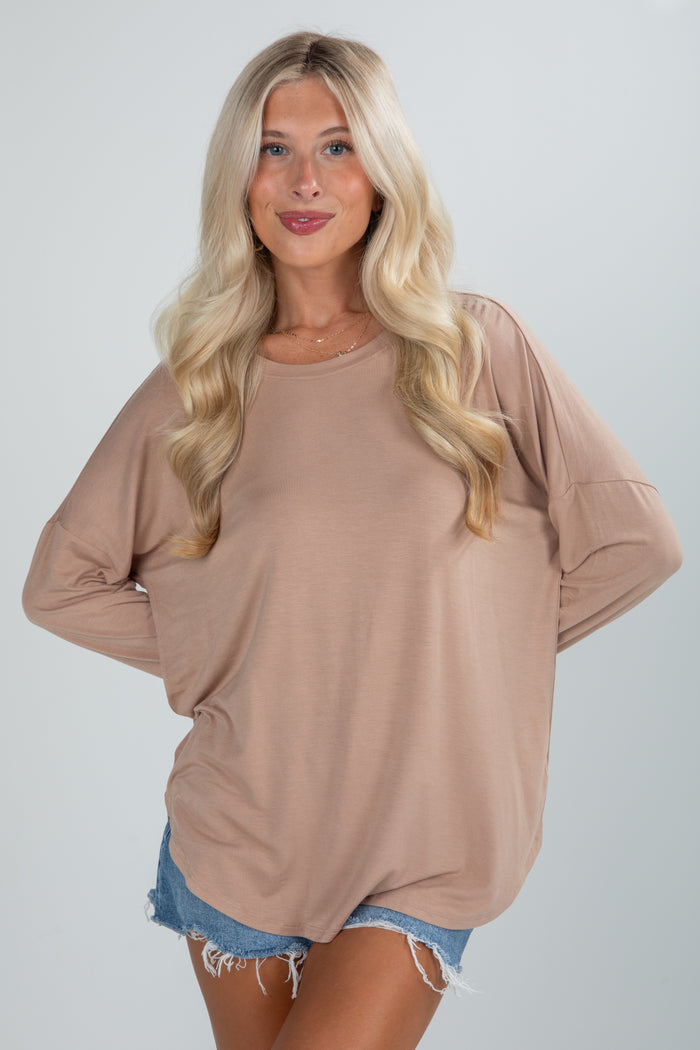 Woman wearing a beige oversized sweater and denim shorts on a plain background