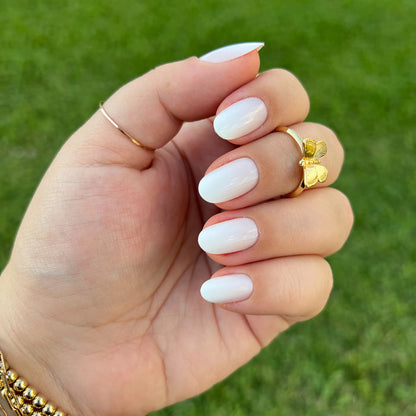 CCT Gradient - Press-On | Short | Round hand with white to sheer pink gradient short round false nails on green grass background