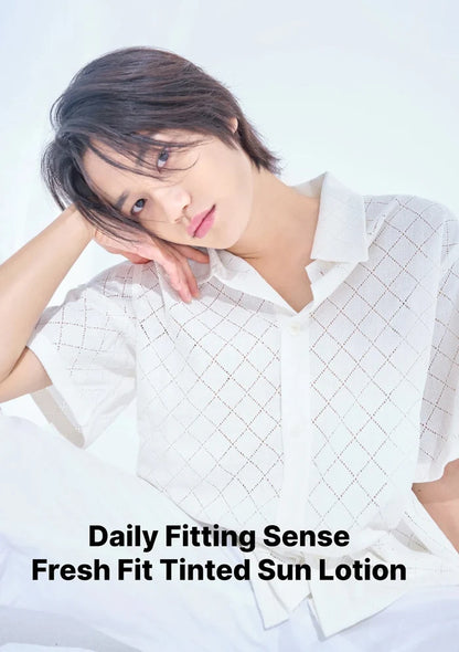 A model wearing a white short-sleeve collared shirt with a subtle grid pattern, posing against a bright white background. Text at the bottom reads 'Daily Fitting Sense Fresh Fit Tinted Sun Lotion'.