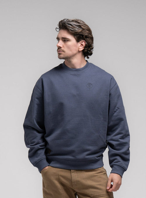 Jack Is 6ft 3" And Wears Size: L | Hem Studio Image Of Model Wearing Dissident Jumper In Storm Blue (SS Model)