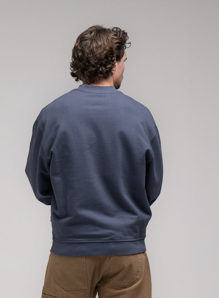 Jack Is 6ft 3" And Wears Size: L | Hem Studio Image Of Model Wearing Dissident Jumper In Storm Blue (SS Model)