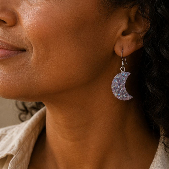 Close-up of a woman wearing a sparkling crescent moon earring.