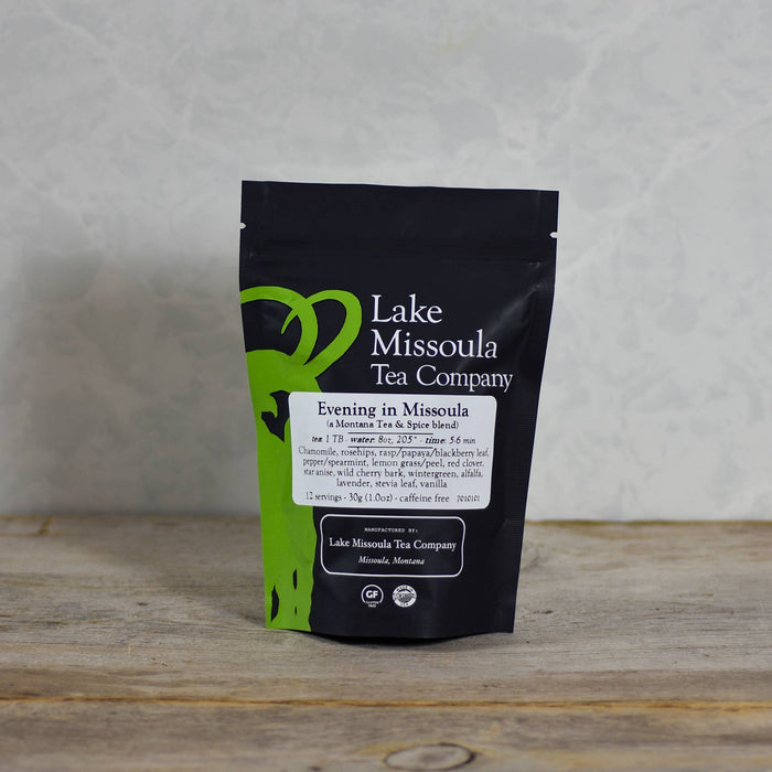 A steaming cup of Lake Missoula Tea Company's Evening in Missoula herbal tea with fresh herbs and lemon slices on a rustic table.