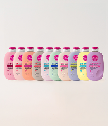 A row of ten eos Body Lotion bottles in assorted pastel colors, including pink, peach, gray, mint, lavender, and yellow, arranged against a light beige background.