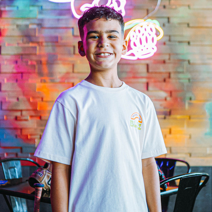 Young boy wearing a white t-shirt with a BL101 logo in front of a colorful neon-lit wall.