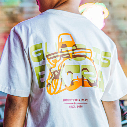 Person wearing a white t-shirt with colorful 'GUAC IS EXTRA' graphic design and text on the back.