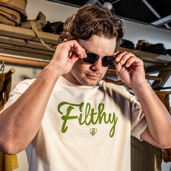 Beige T-shirt with olive green ‘Filthy’ lettering and BL101 logo across chest on person.