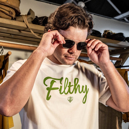 Beige T-shirt with olive green ‘Filthy’ lettering and BL101 logo across chest on person.