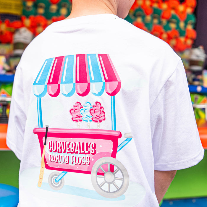 Person wearing a white t-shirt with a candy floss cart design in front of a colorful background.