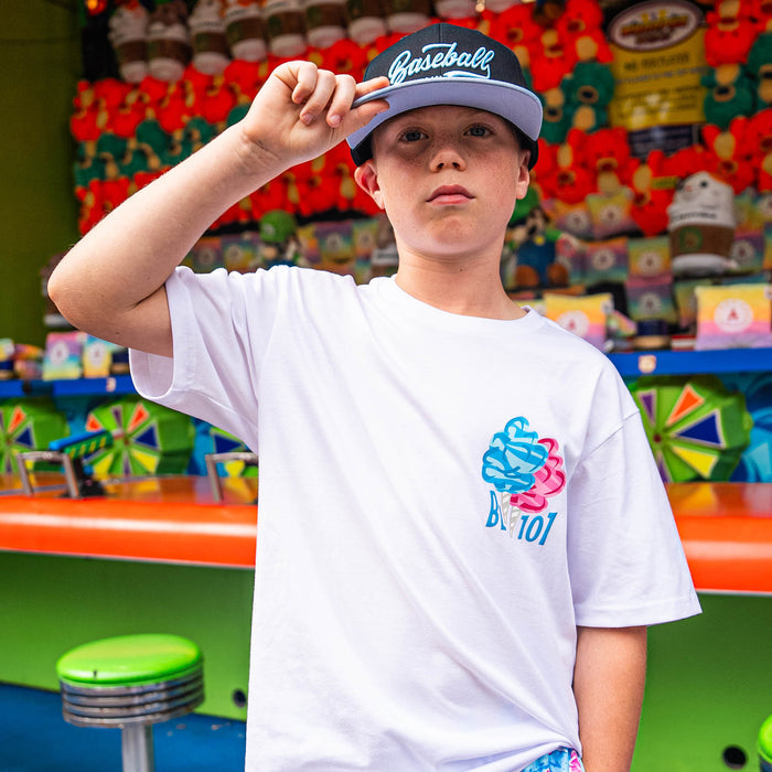 Child wearing a white t-shirt with pink and Blue cotton candy BL101 design and a baseball cap in front of a colorful background