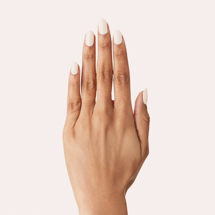 Hand with LHG nail polish in a fresh neutral shade with subtle pink on neatly manicured nails against a pale background