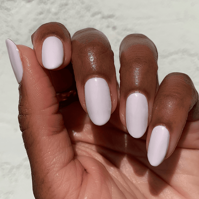 Close-up of a hand with LHG nail polish in a soft neutral shade finished with a smooth manicure against a light background