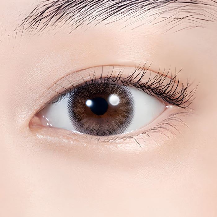 Close-up of an eye wearing Lilmoon Monthly Flamingo prescription and non-prescription colored contact lenses. Soft pink and sheer gray circle lenses with a two-tone gradient create a glossy, romantic eye look while naturally enhancing dark brown eyes. Monthly Japanese colored contacts with a delicate blush undertone, smoky halo, natural enlargement effect, and comfortable everyday wear.