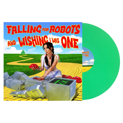 The L0L0 album cover for Falling for Robots and Wishing I Was One features a woman in a Dorothy costume repairing a robot on a yellow brick road, with a green vinyl visible—hot girls in hell vibes, but with sparks and heart.