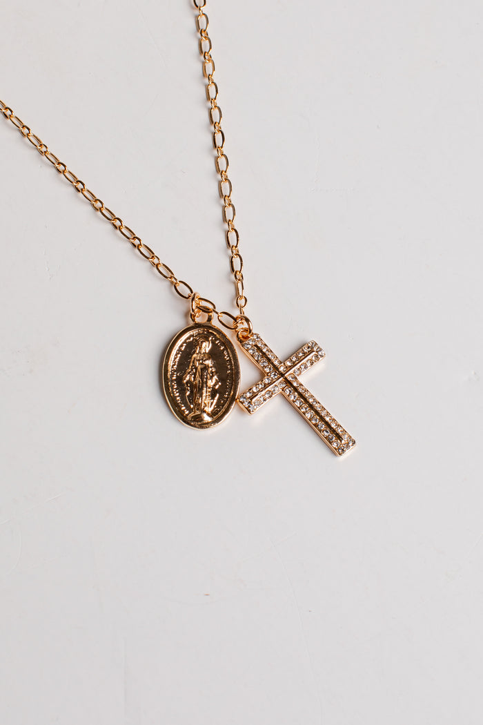A rose gold chain necklace featuring two pendants: an oval Miraculous Medal pendant and a rectangular cross paved with small clear stones, displayed on a light gray background.
