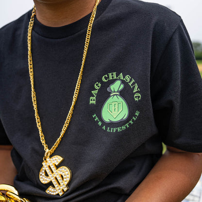 Person wearing a black t-shirt with 'Bag Chasing It's a Lifestyle' logo and a gold chain with a dollar sign pendant.