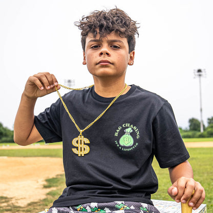 Child holding a gold chain with a dollar sign pendant on a sports field