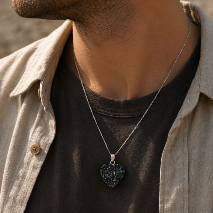 Person wearing a necklace with a heart-shaped pendant, close-up on neck and shirt collar.