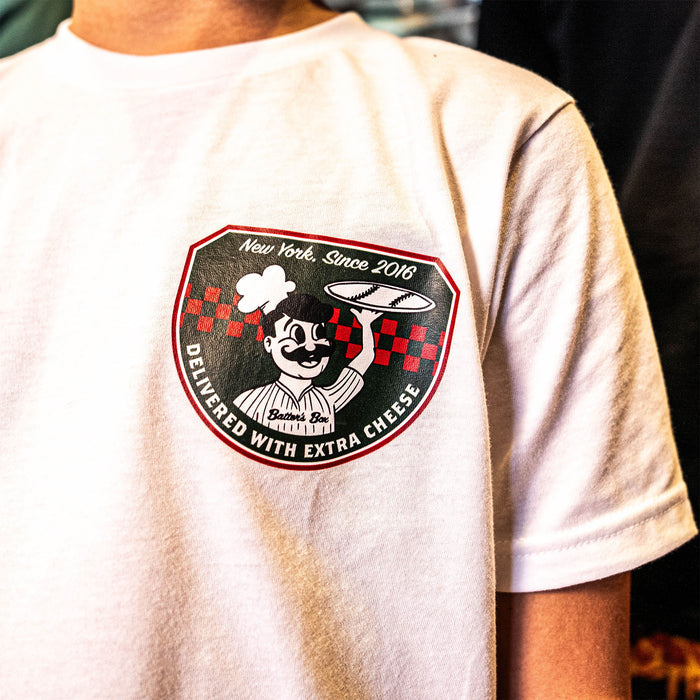 Youth model wearing white youth graphic tee with “Pizza Shop” design