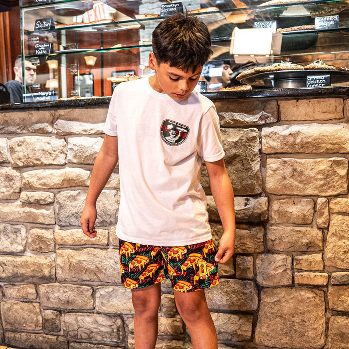 Youth model wearing white youth graphic tee with “Pizza Shop” design