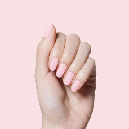 Hand with nails painted in soft rose pink Rosy Tips gel polish on pale pink background showing manicure quality