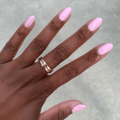 Hand with glossy nails painted in Rosy Tips gel polish showing smooth manicure on neutral gray background