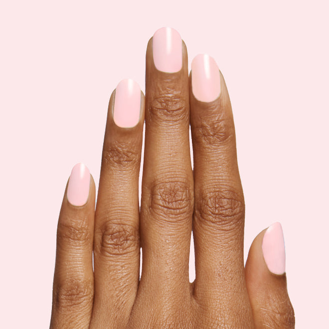 Hand with smooth SCL soft bubblegum pink polish on nails against a pale pink background for a fresh mani