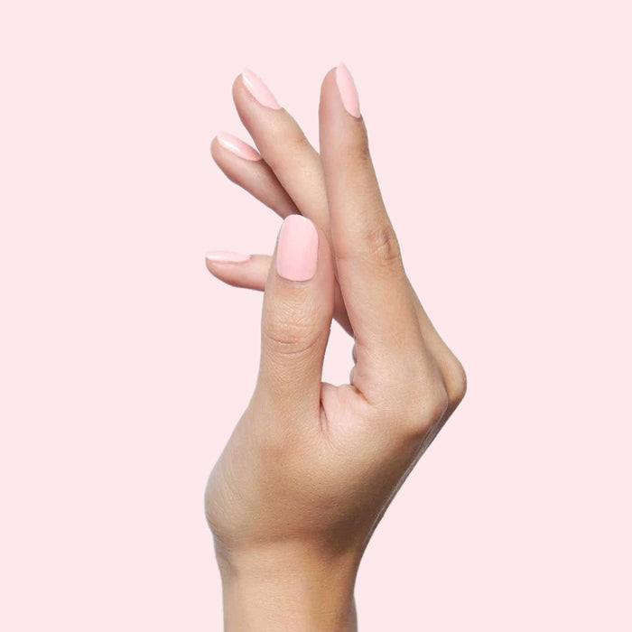 Hand with smooth SCL soft bubblegum pink gel polish on nails against a pale pink background for a fresh mani