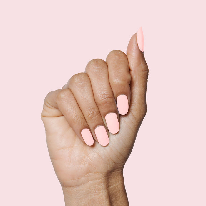 Hand showcasing SCL soft bubblegum pink gel polish on neatly shaped nails against a pale pink background for a mani