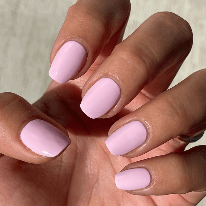 Close-up of hand with SCL soft bubblegum pink gel polish on neatly shaped nails in natural light for a manicure