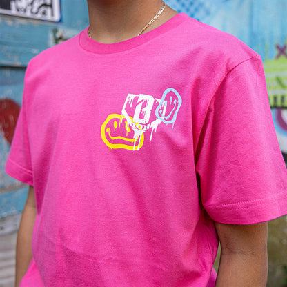 Youth model wearing pink youth graphic tee with “Smiley Slugger” design