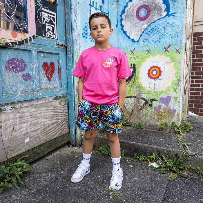 Youth model wearing pink youth graphic tee with “Smiley Slugger” design