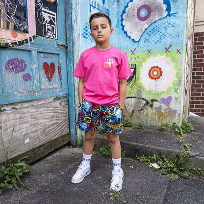Youth model wearing pink youth graphic tee with “Smiley Slugger” design
