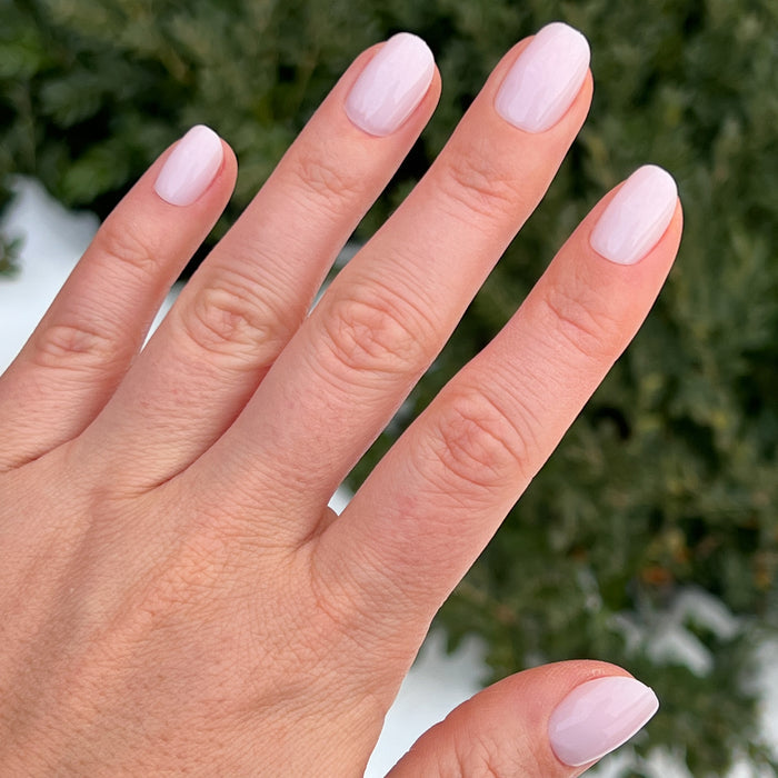 Hand wearing Strawberry Scone - Press-On | XS | Round with extra-short, semi-sheer pink false nails manicure style outdoors