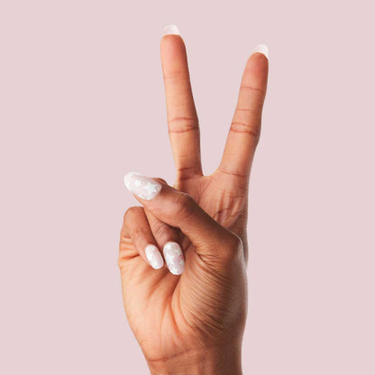 Super Stars - Press-On | Short | Round hand showing short round false nails with white stars on neutral base against pink background