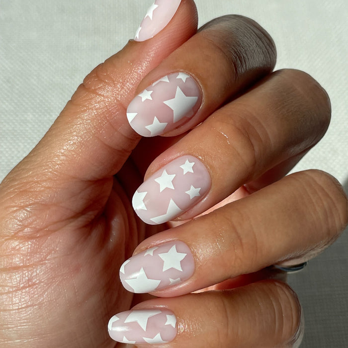Super Stars - Press-On | Short | Round hand with short round neutral nails featuring white star design on natural skin tone