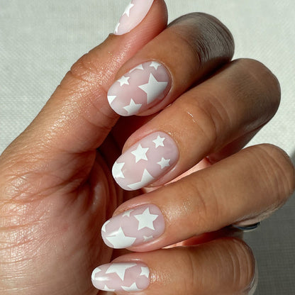Super Stars - Press-On | Short | Round hand with short round neutral nails featuring white star design on natural skin tone