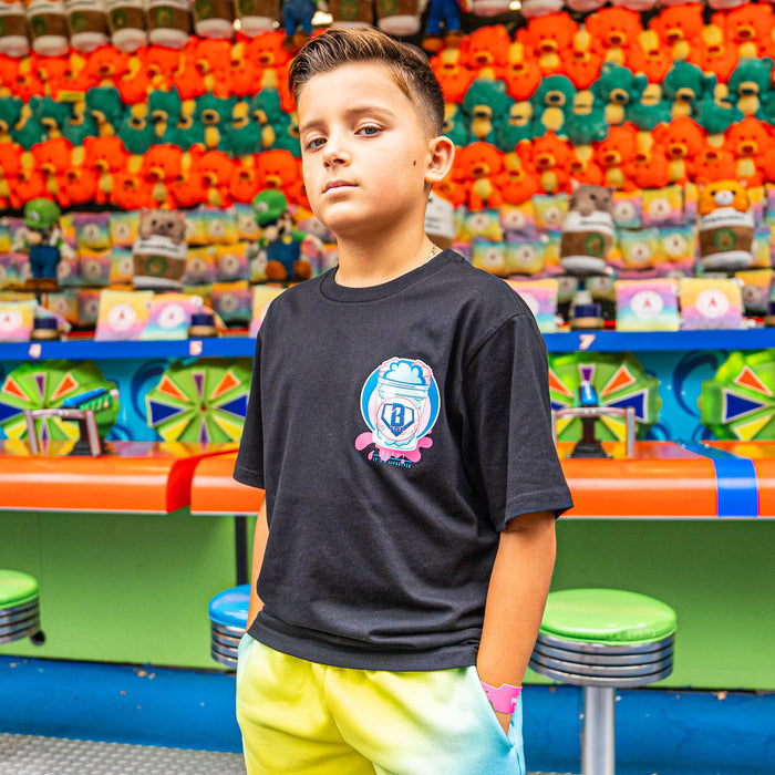 Child wearing a black t-shirt with a cotton candy BL101 design in front of colorful arcade games