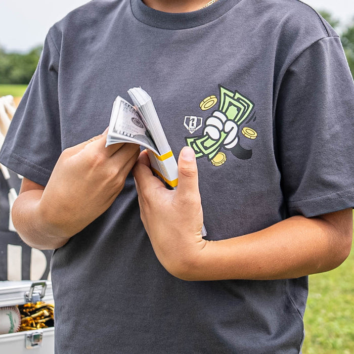 Person wearing a gray t-shirt with a hand holding money graphic design, holding money outdoors.