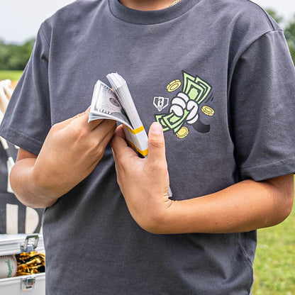 Person wearing a gray t-shirt with a hand holding money graphic design, holding money outdoors.